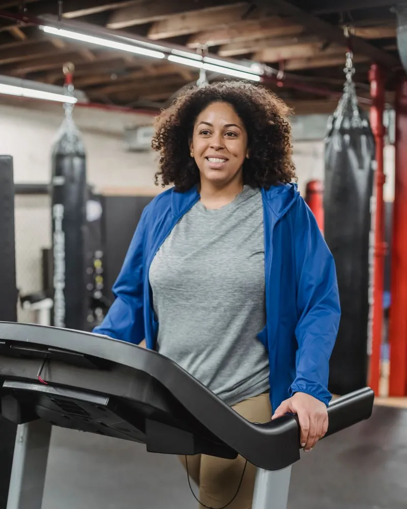 Mulher sorrindo, caminhando na esteira da academia