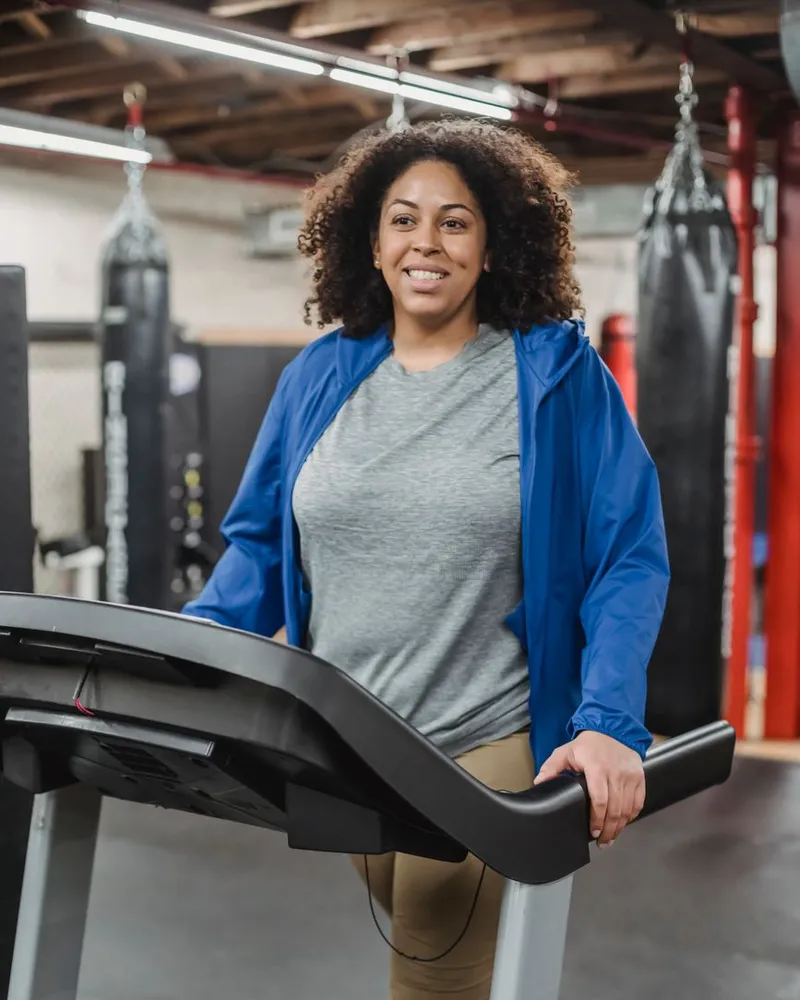 Mulher sorrindo enquanto caminha na esteira da academia